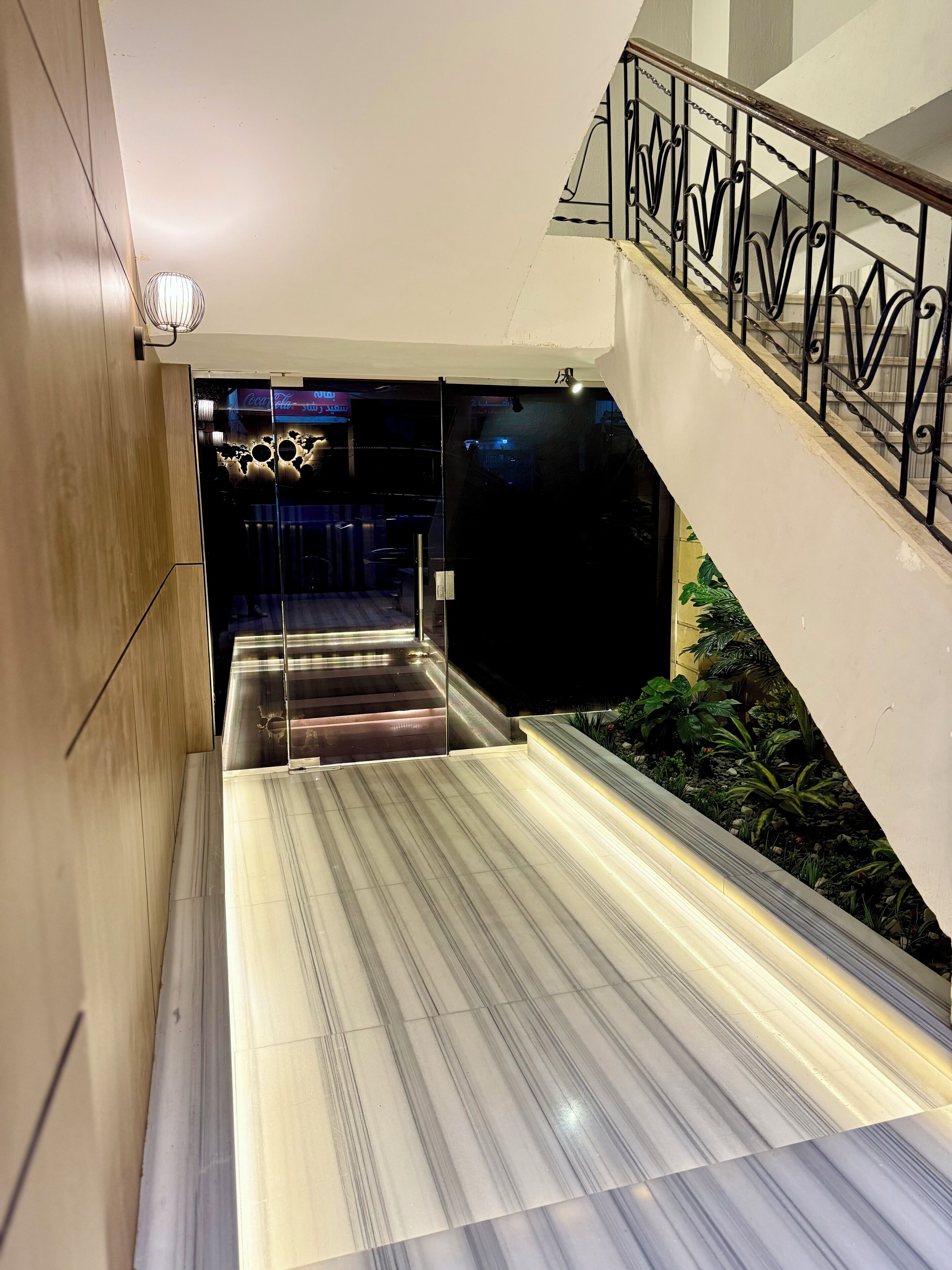 A modern interior with a marble staircase, glass doors, and a metal railing.