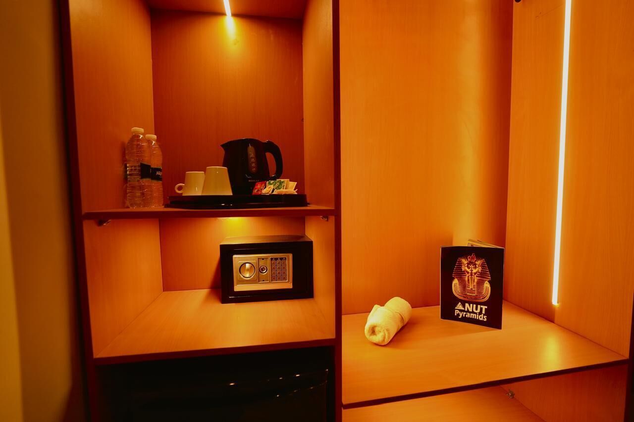 Une chambre d’hôtel avec un intérieur en bois, une radio, une bouilloire et un livre intitulé « Une pyramide de noix ».