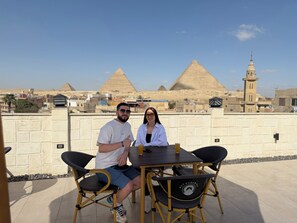 Two people seated at a table with a view of the pyramids in the background.