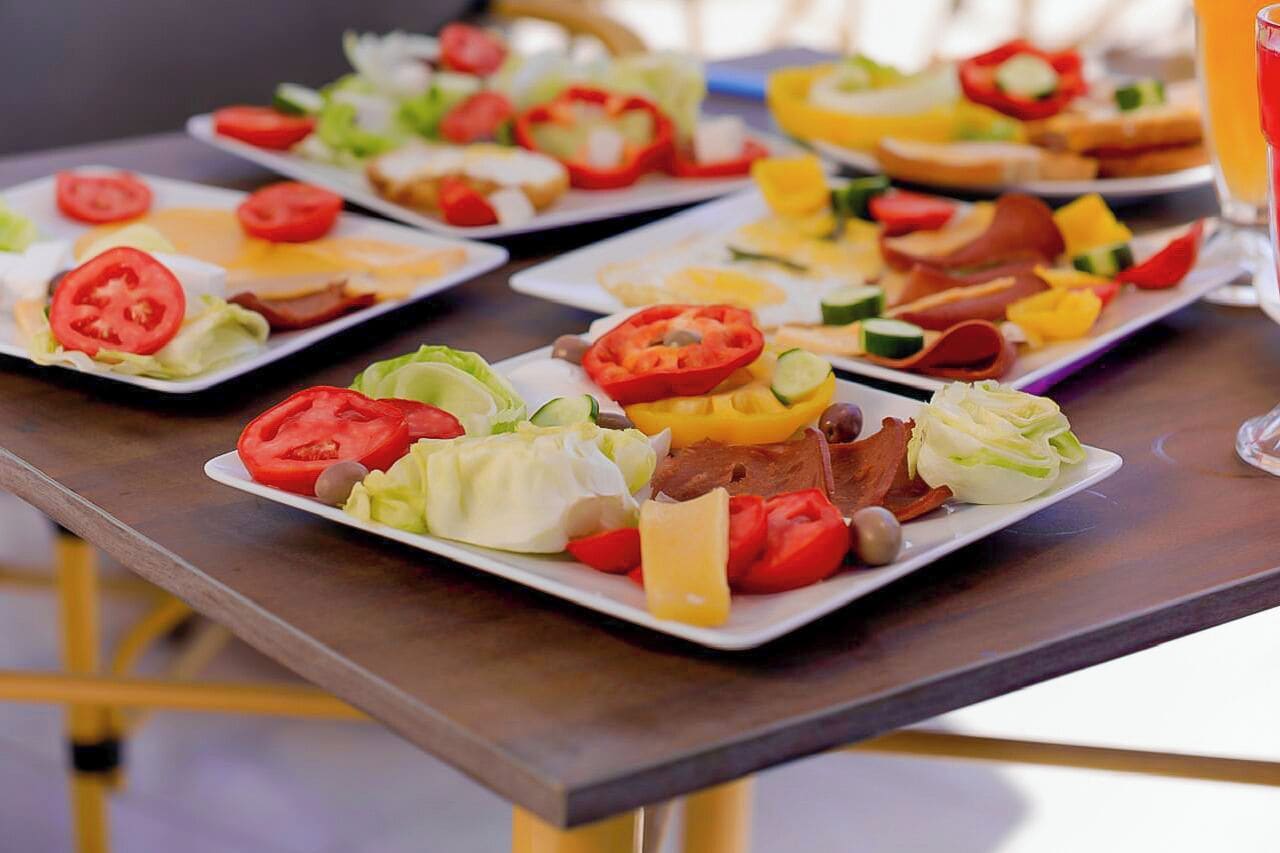 A table with various plated dishes including salads, sandwiches, and fruit.