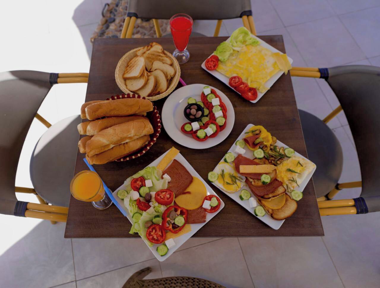Une table garnie de divers aliments pour le petit-déjeuner, notamment du pain, des œufs et des salades.