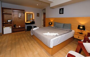 Un dormitorio con una cama, mesitas de noche, un armario, un espejo y un escritorio pequeño.