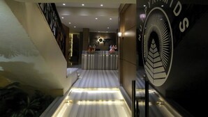 A hotel reception area with a reception desk, a large emblem on the wall, and a staircase leading to another floor. - Nut Pyramids View (Giza)