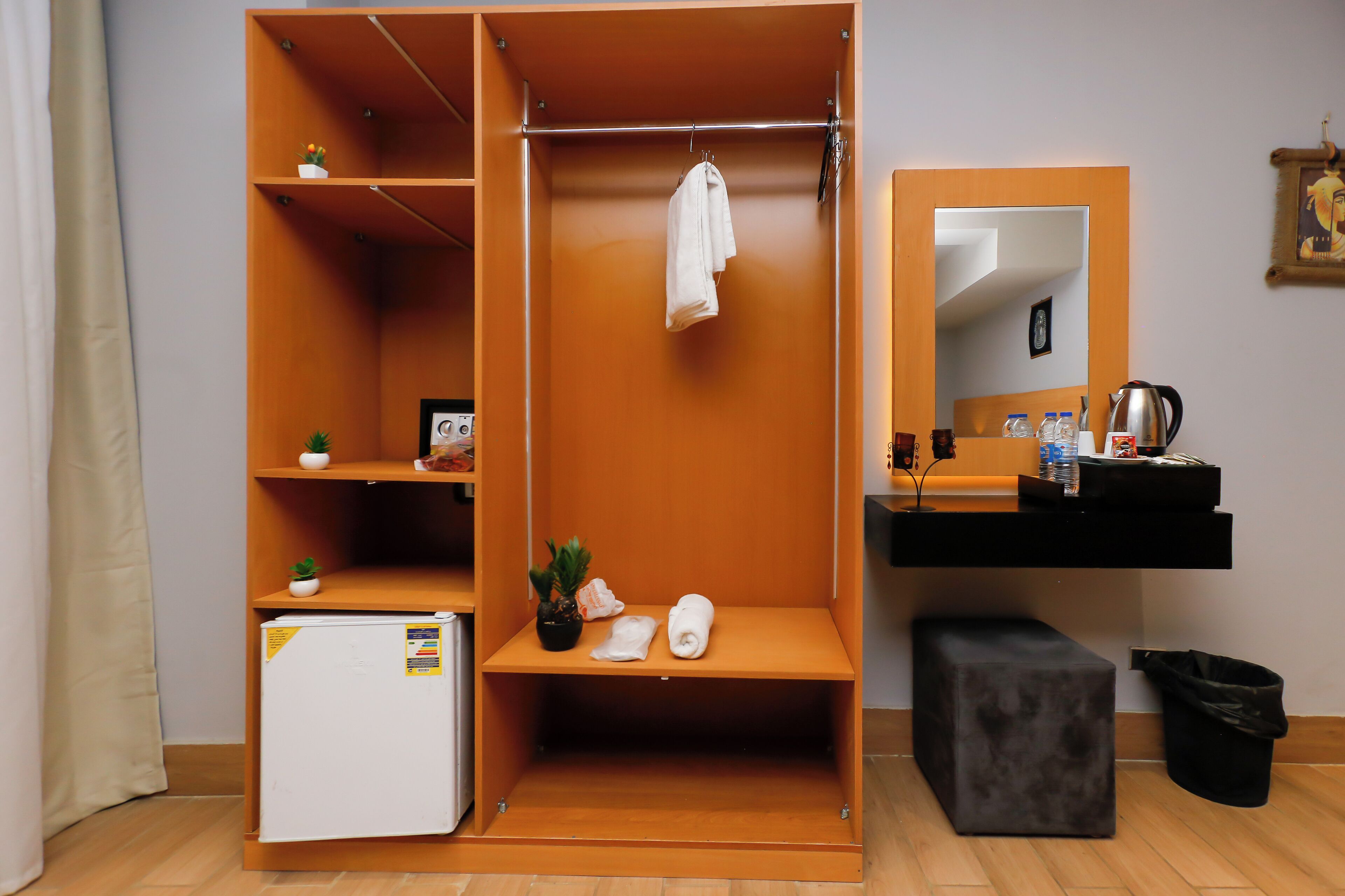 Habitación compacta con armario empotrado, un pequeño rincón de descanso, un espejo y una kitchenette.