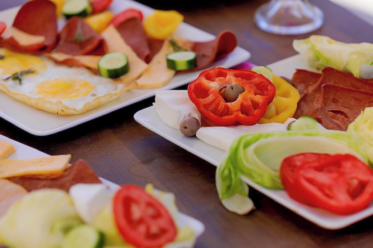 A table with various breakfast items including eggs, meats, and vegetables.