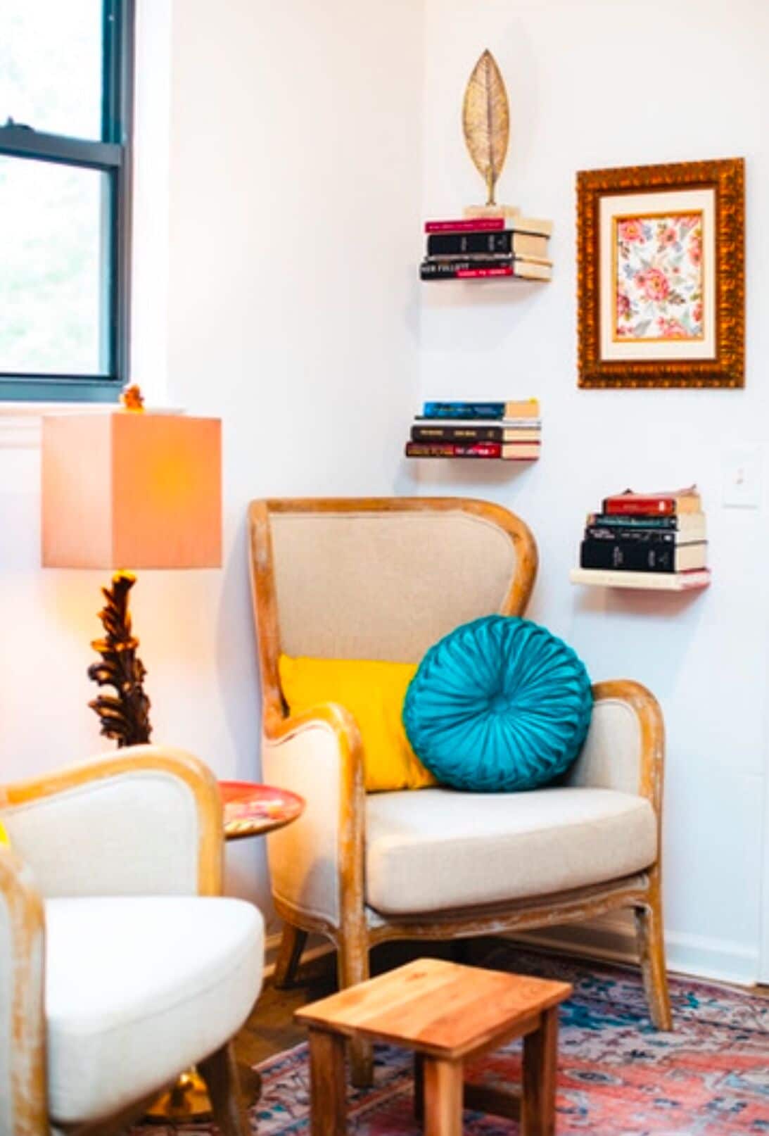 A cozy room with a rattan chair, a small wooden table, and a bookshelf with books and decorative items.