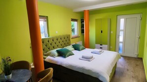 Een kamer met een bed, een tafel met stoelen en een potplant.