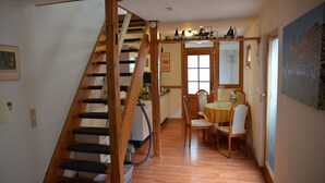 Un escalier en bois mène à un espace repas comprenant une table et des chaises.