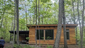 A modern wooden cabin surrounded by trees in a forest.