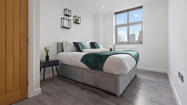 A modern bedroom with a bed, bedside table, and a window. - City Centre Luxury ApartmentSofa BedWIFI (Leicester)