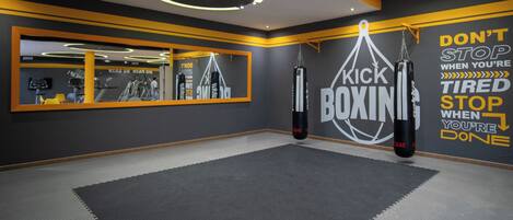 A gym with a mirrored wall, punching bags, and motivational wall art.