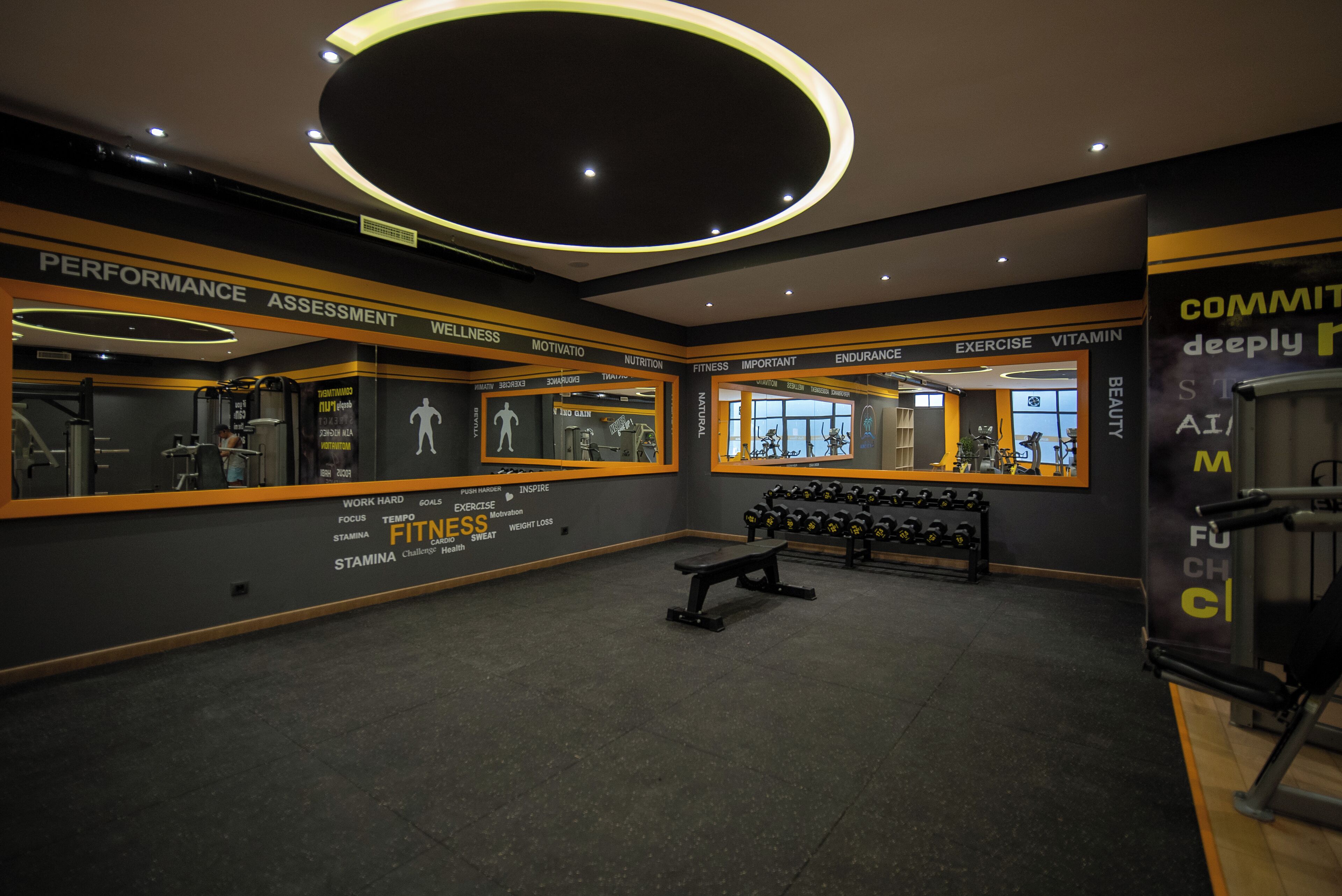 A gym with mirrored walls, weight racks, and motivational posters.