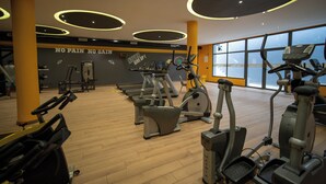 Een fitnessruimte met diverse trainingsapparaten, een motiverende muur en grote ramen.