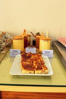 Una presentación de postres con un plato de rebanadas, dos frascos etiquetados como 'GOIABADA' y 'MARGARINA', y una cuchara de madera.