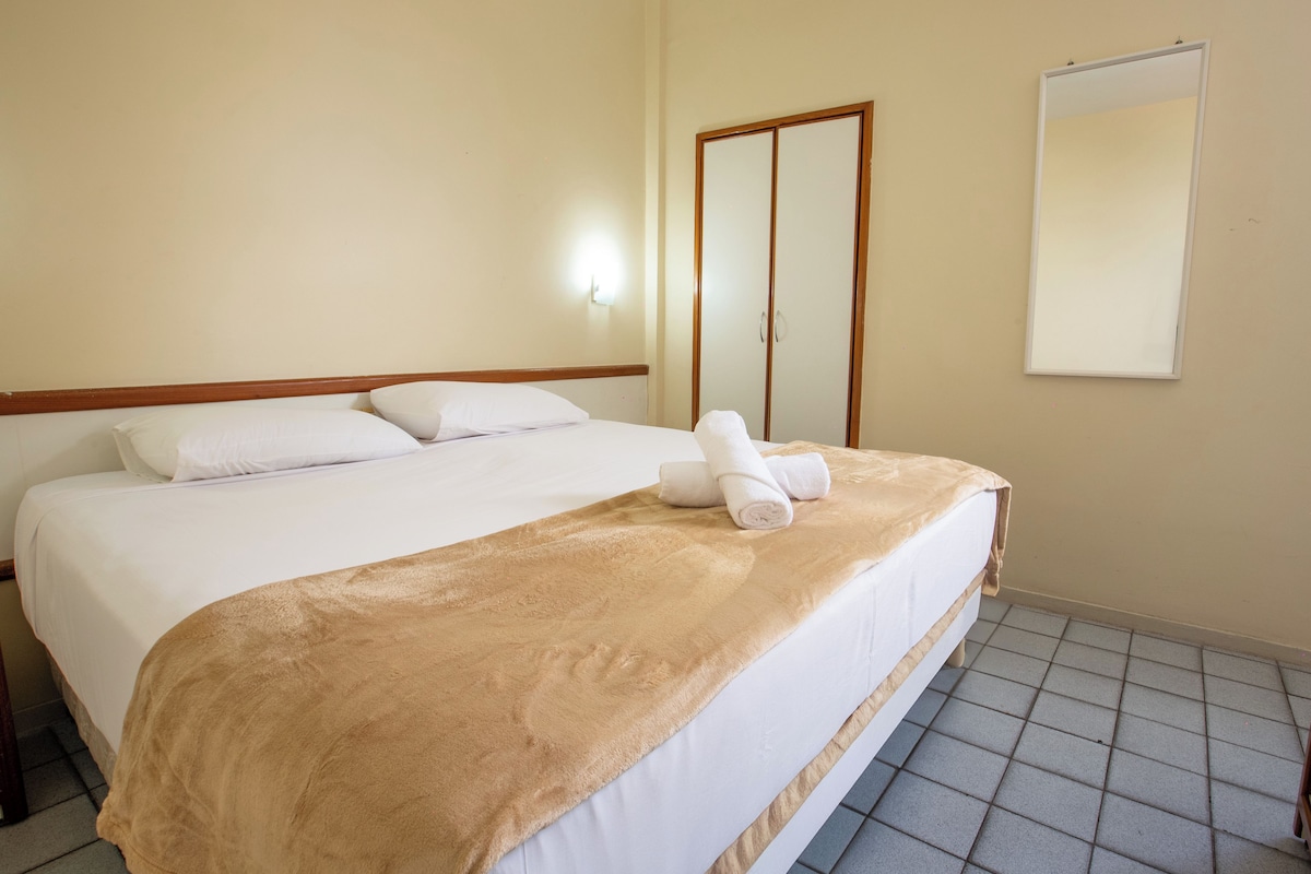 A hotel room with a bed, a wardrobe, and a mirror.