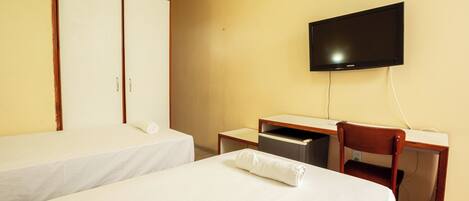 Una habitación de hotel con dos camas individuales, un escritorio con silla, un televisor y un armario.