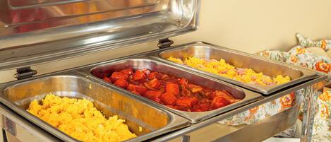 A buffet with various dishes including scrambled eggs, sausage, and rice.
