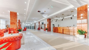 A spacious lobby with a reception desk, red seating area, and a marble floor. - Casa Costa (Bar)