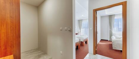 Habitación de hotel con armario de madera, suelo de mármol y cama con ropa de cama blanca.