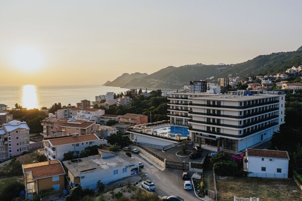 A hotel with a rooftop pool, surrounded by residential buildings, and a view of the sea and hills in the background. - Casa Costa (Bar)