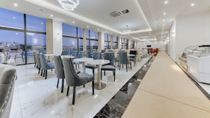 A modern restaurant with a long counter, ample seating, and large windows offering city views. - Casa Costa (Bar)