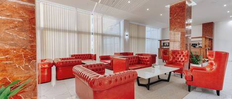 Una sala de estar moderna con sofás de cuero rojo, una mesa de centro blanca y piso de mármol.