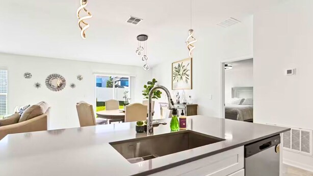 Una cocina moderna con una isla central, electrodomésticos de acero inoxidable e iluminación colgante.
