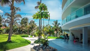 Un hotel moderno con un patio amplio, palmeras y fachada de vidrio.