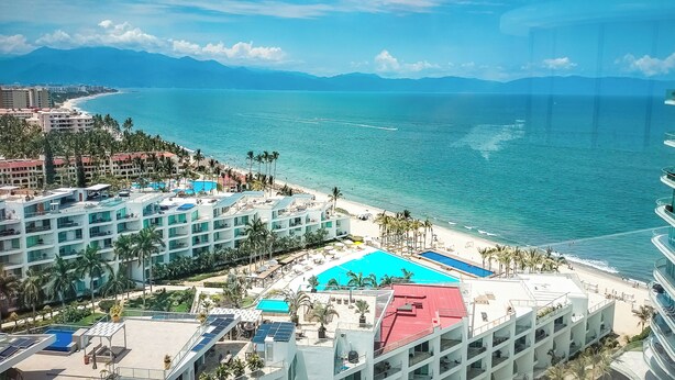 Un resort con varias piscinas, una playa y vistas al océano y las montañas.