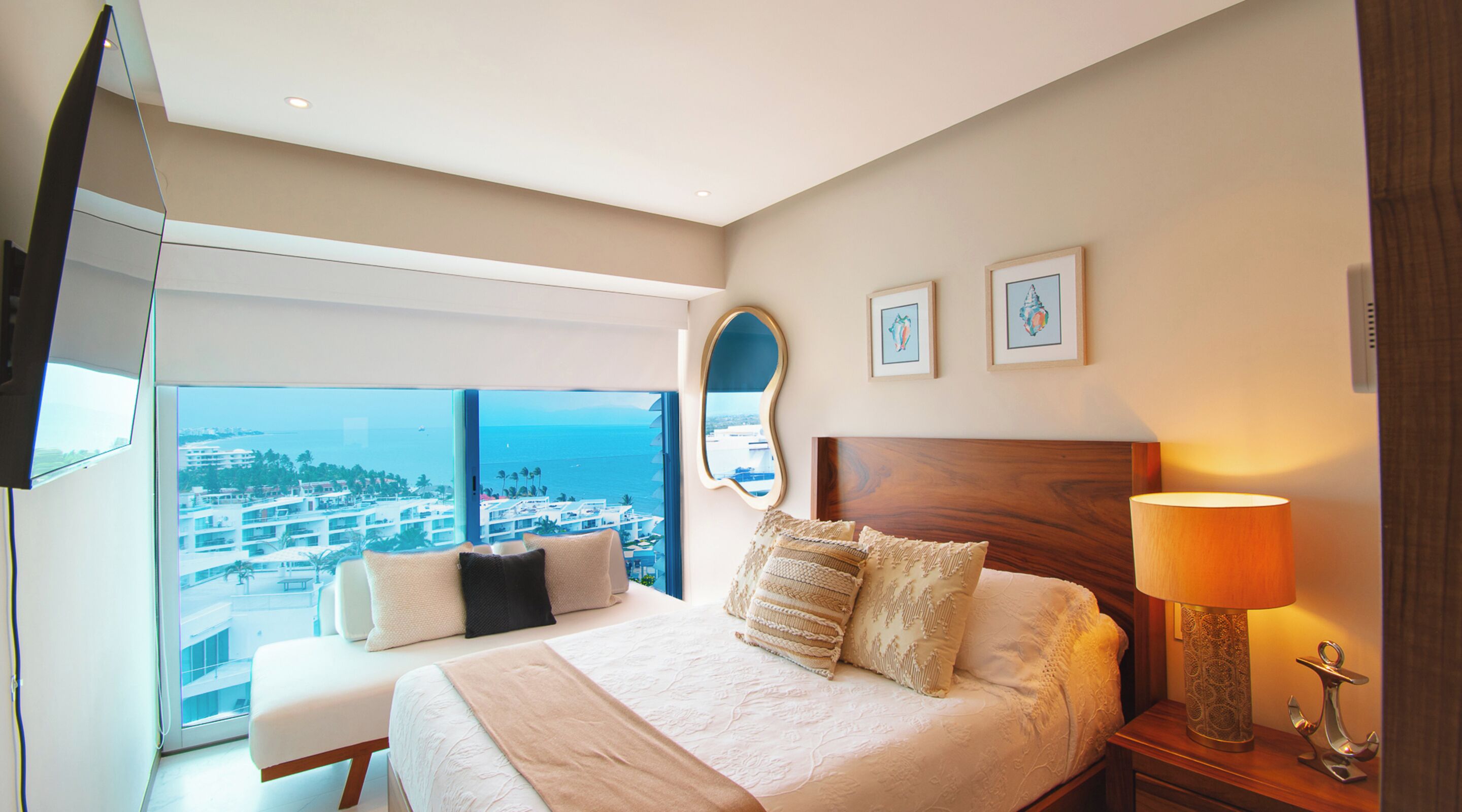 A hotel room with a large bed, a TV, a view of the city, and a balcony.