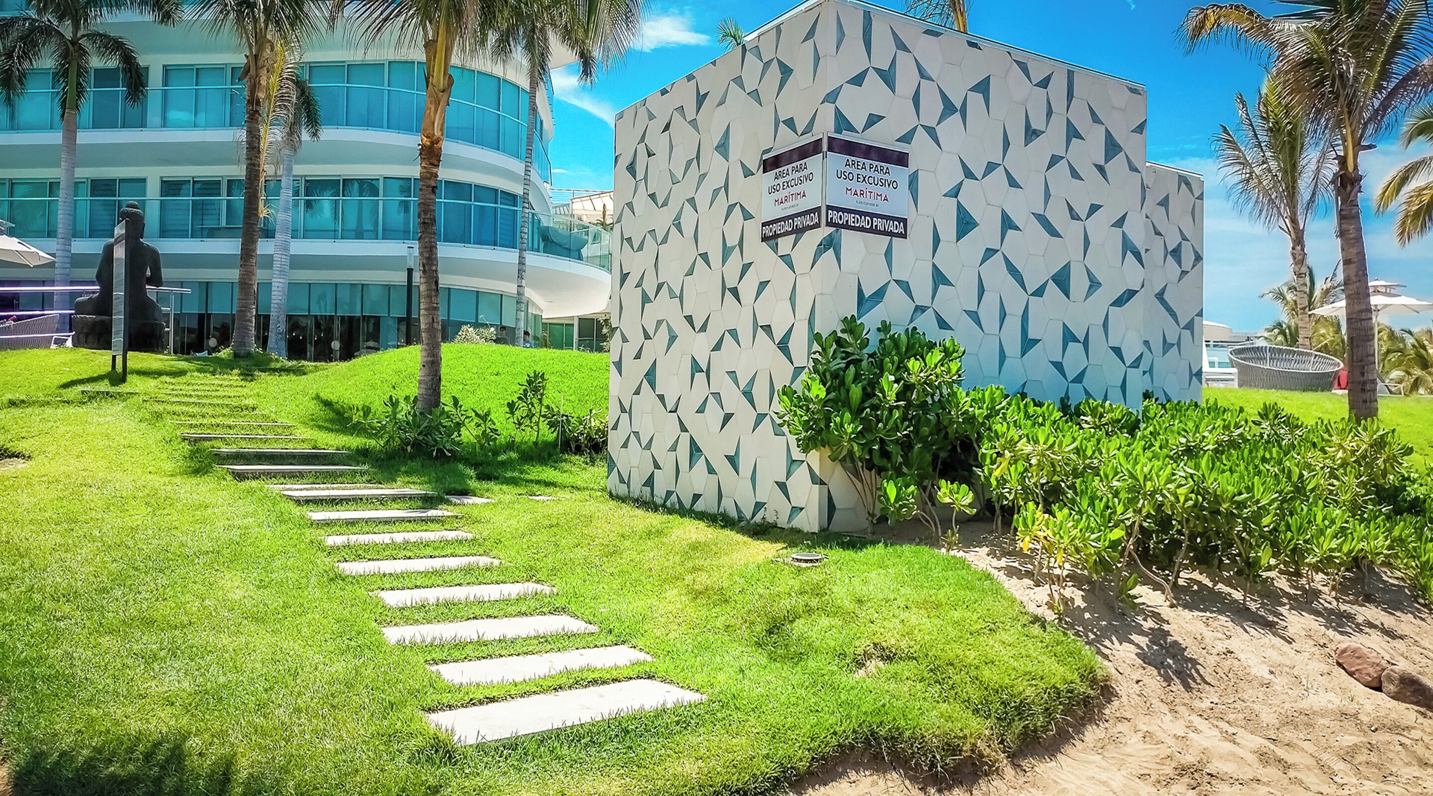 Ein modernes Gebäude mit geometrischer Fassade, ein Verbotsschild für Privatgrundstück und eine gepflegte Rasenfläche mit einem Steinweg.
