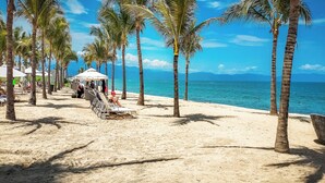 Una playa con palmeras, tumbonas y una sombrilla.