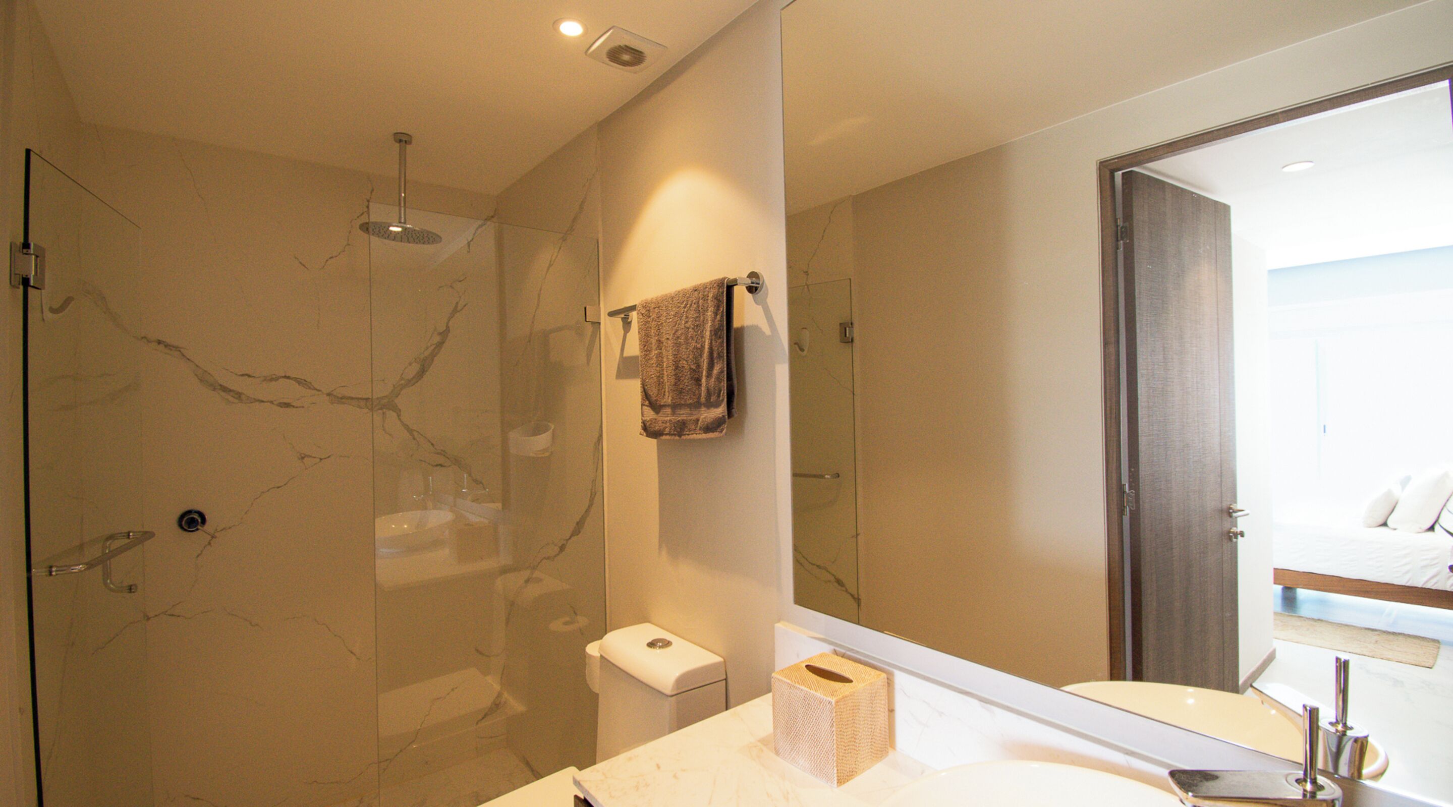 A modern bathroom with a glass-enclosed shower, a white sink, and a large mirror.