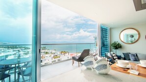 Un balcón amplio con vista al mar, amueblado con una mesa redonda, sillas y jarrones decorativos con forma de pez.