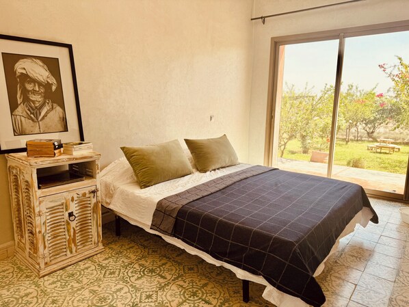 Un dormitorio con cama, cómoda, un cuadro enmarcado y vistas al exterior.