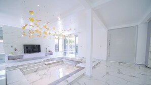 Un intérieur spacieux avec un sol en marbre, un grand espace salon et un téléviseur.