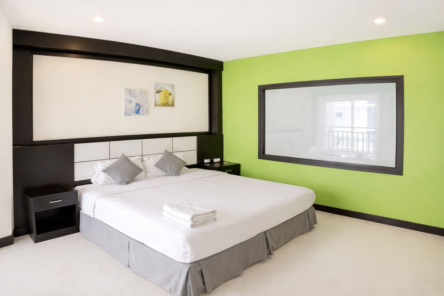 A modern hotel room with a large bed, a nightstand, a bedside table, and a large window with a view.
