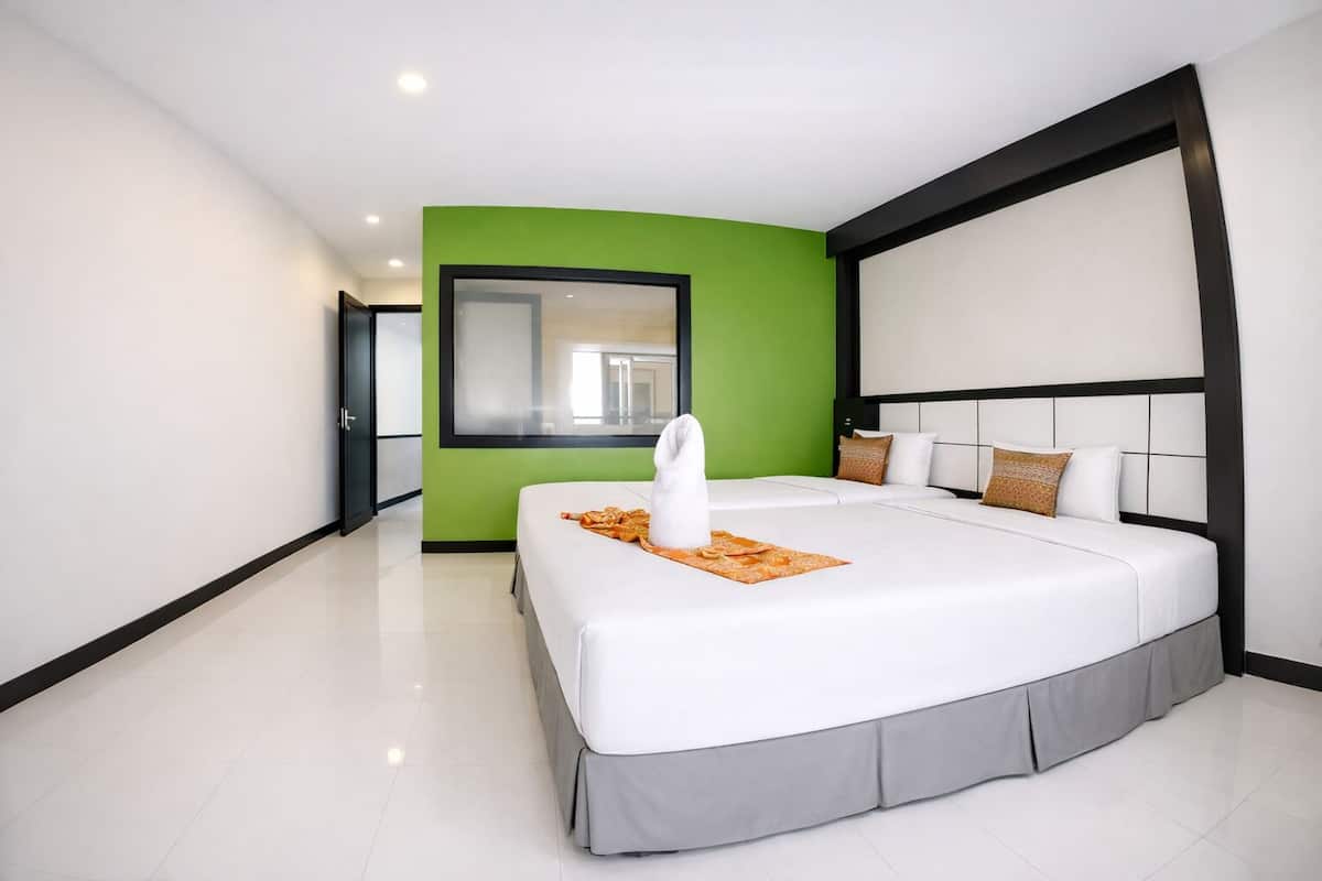 Ein modernes Hotelzimmer mit einem großen Bett, grünen Akzentwänden und einem großen Fenster.