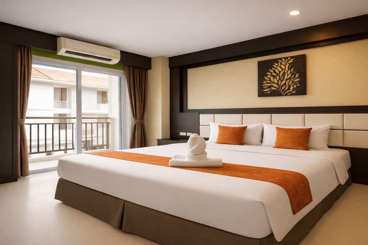 Ein Hotelzimmer mit einem großen Bett, einem Balkon und einer Wand-Klimaanlage.
