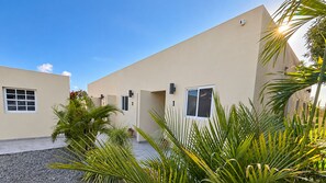 Un bâtiment moderne avec des portes numérotées, un ciel dégagé et une végétation luxuriante.