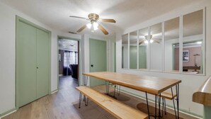 A room with a wooden table and benches, a ceiling fan, and a large mirror. - Bloomingdale - Mesa A - Retro! - 4BR Near Sav Airport (Bloomingdale)