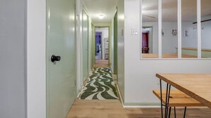 A hallway with a patterned rug, a wooden table, and a mirrored wall. - Bloomingdale - Mesa A - Retro! - 4BR Near Sav Airport (Bloomingdale)
