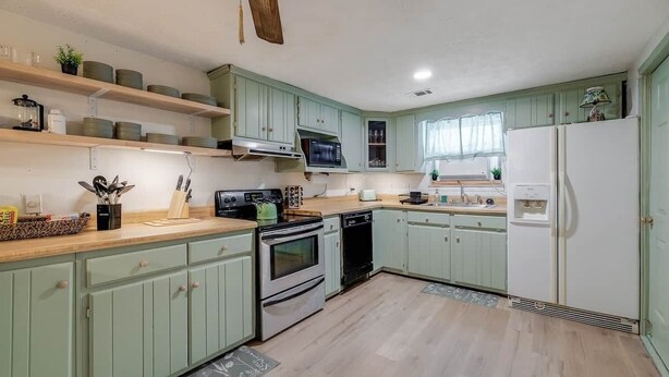 A kitchen with green cabinets, a microwave, stove, and a refrigerator. - Bloomingdale - Mesa A - Retro! - 4BR Near Sav Airport (Bloomingdale)