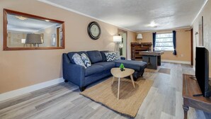 A living room with a sofa, a coffee table, a clock, and a television. - Bloomingdale - Mesa A - Retro! - 4BR Near Sav Airport (Bloomingdale)
