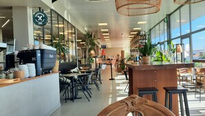 Interior de cafeteria moderna amb màquina de cafè, zona de seients i grans finestres que ofereixen vistes.