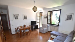Un salon avec un canapé, une table à manger et des chaises, un téléviseur et une fenêtre donnant sur un beau paysage.