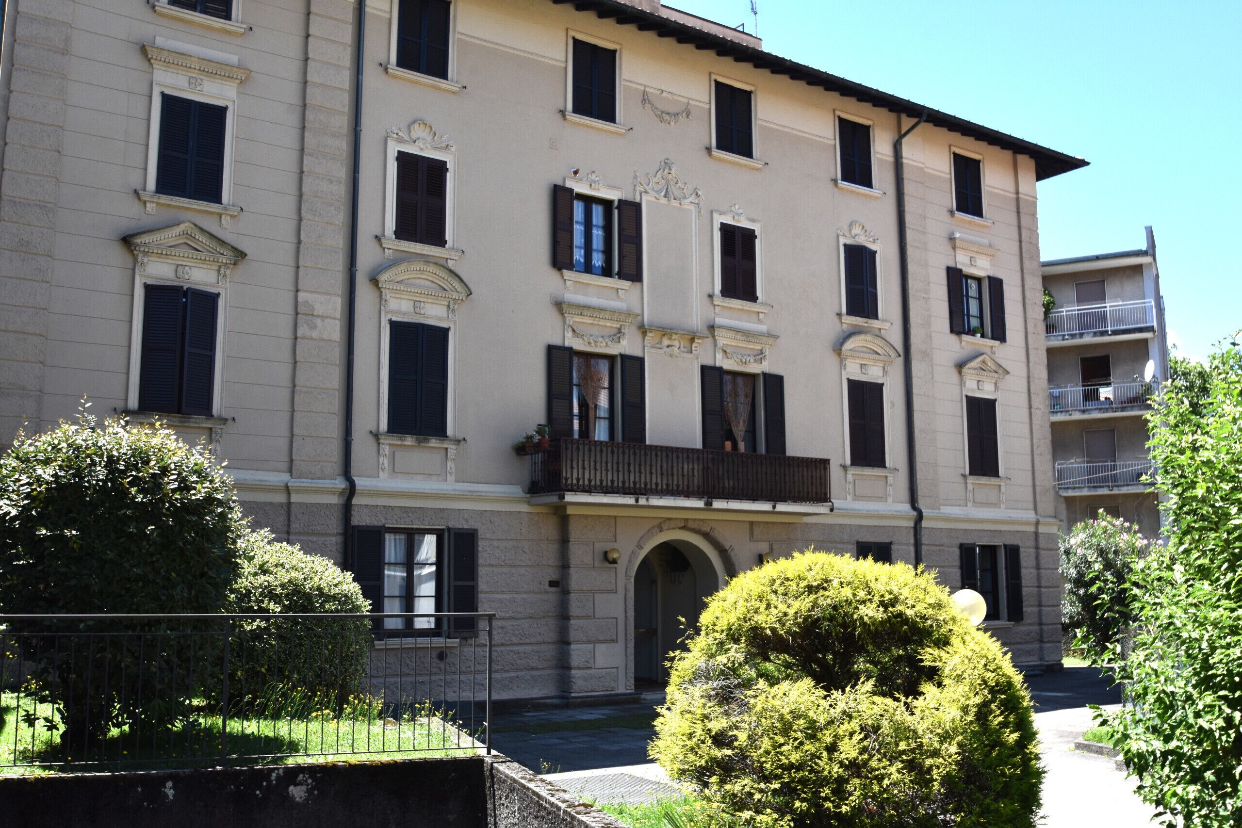 A multi-story building with a symmetrical facade, large windows with shutters, and a central entrance with an archway.