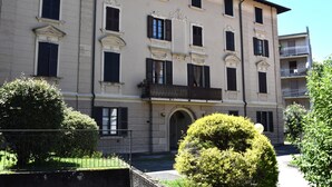 Un immeuble à plusieurs étages, doté d’une façade symétrique, de grandes fenêtres avec volets et d’une entrée centrale surmontée d’une arche.