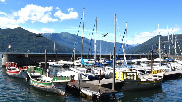Un port de plaisance avec des bateaux amarrés à un quai, entouré de montagnes.