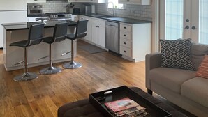 Een moderne keuken met witte kastjes, roestvrijstalen apparatuur en een bar voorzien van krukken.